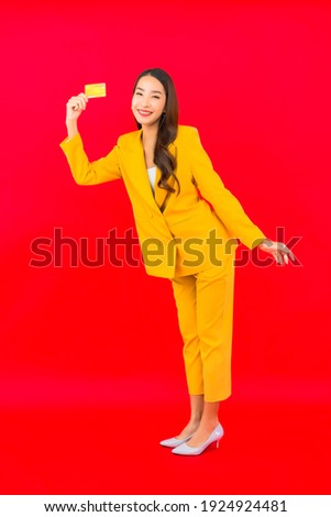 Portrait beautiful young asian woman use mobile with credit card on red background
