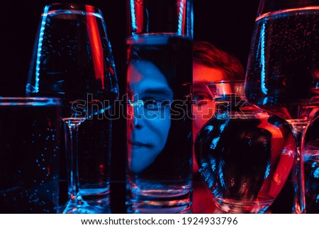 psychedelic portrait of a strange man looking through glasses of water with blurring and red and blue neon lights