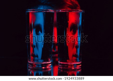 surreal portrait of a man looking through glass glasses of water with reflections and distortions with red blue neon light