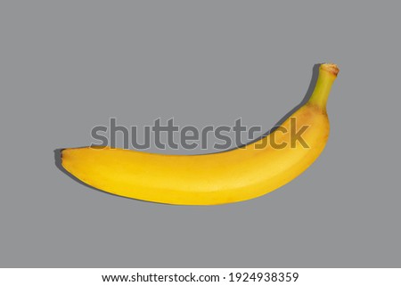 One ripe illuminating yellow banana on the ultimate gray background color 2021