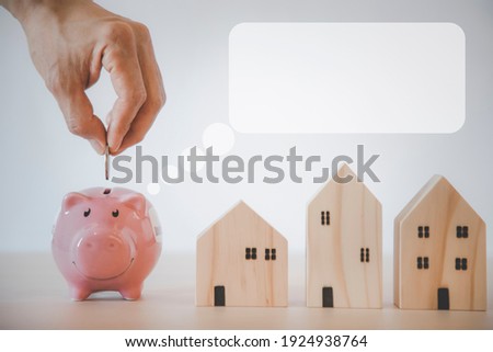 Hand hold Coins and pink piggy with icon business with Mini wood house model from model on wood table, Planning buy Real Estate, Planning to buy property and Choose the best, saving money concept.