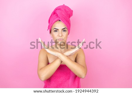 Young beautiful woman wearing shower towel after bath standing over isolated pink background Rejection expression crossing arms doing negative sign, angry face