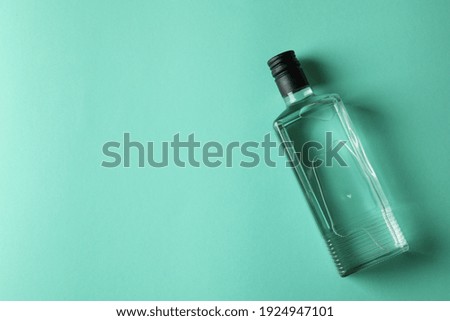 Blank bottle of vodka on mint background, space for text
