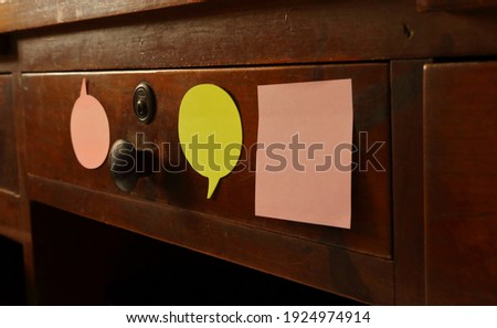 Blank sticky notes attached to vintage drawer, selective focus on the green color note 