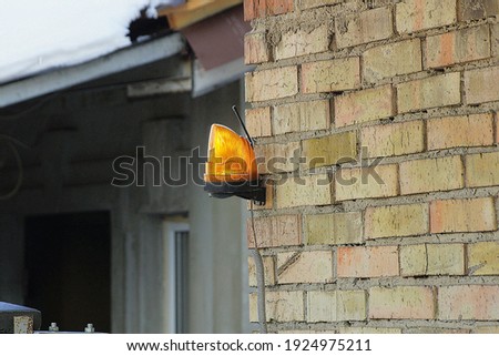 one red signal light hanging on a brown brick wall on the street