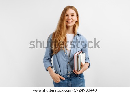 Portrait of smiling pretty young woman holding books and looking at camera isolated on white background