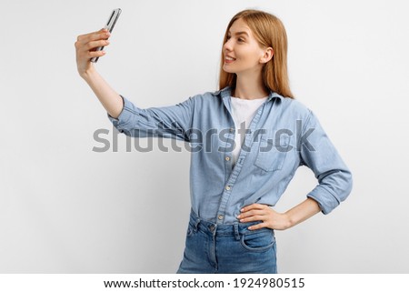 Beautiful happy young woman taking selfie on mobile phone isolated on white background