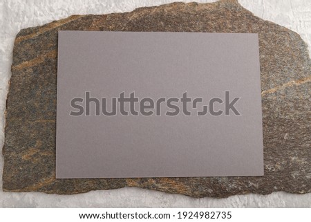 Gray paper business card, mockup with natural stone on gray concrete background. Blank, flat lay, top view, still life, copy space.