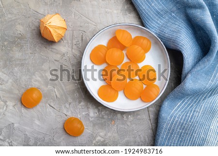 Jelly pumpkin candies on gray concrete background and blue linen textile. close up, top view, flat lay. autumn concept.