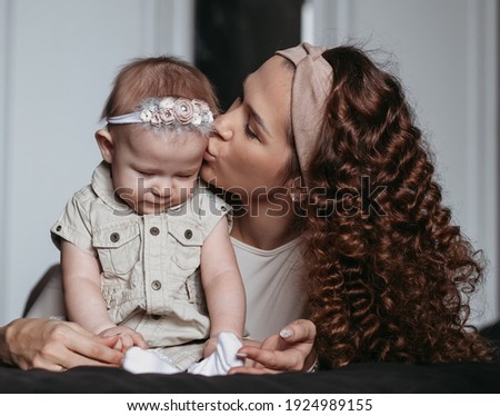 Young mother kisses sad baby girl