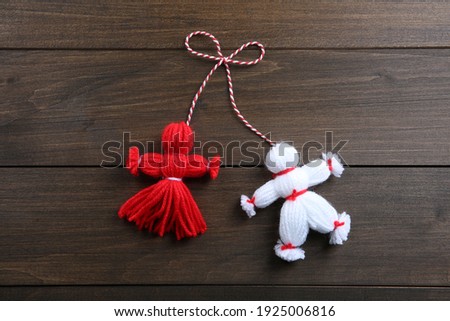 Traditional martisor shaped as man and woman on wooden background, top view. Beginning of spring celebration