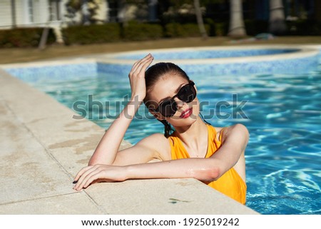 woman in a yellow bathing suit Swims in the pool sunglasses luxury