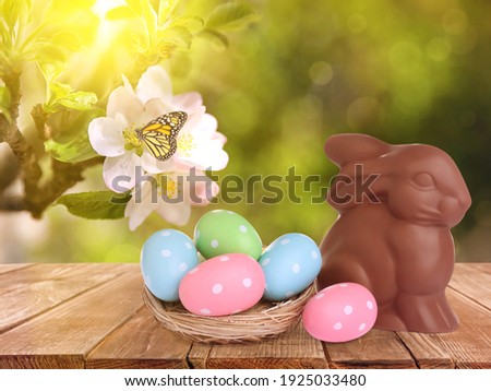 Sweet chocolate bunny and colorful eggs on wooden table outdoors. Easter celebration