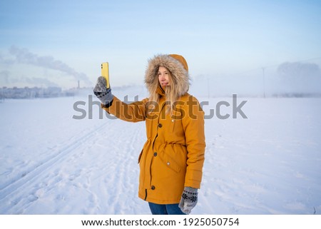 a girl takes pictures on her phone of a landscape in winter. very cold. the north pole. winter landscape and fog in the background