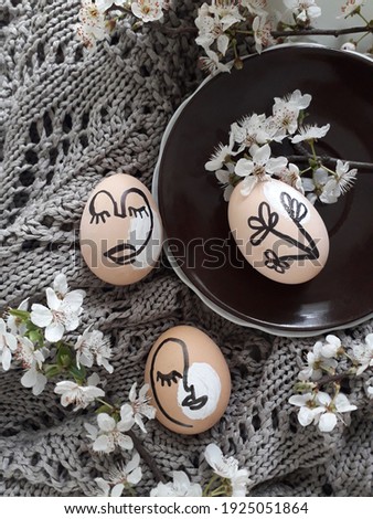 Happy Easter concept. Surreal faces on eggs on dark background. Art and Online style. Spring blossom.Top view. Flat lay.