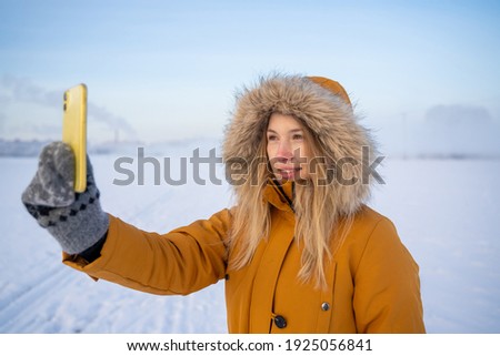 a girl takes pictures on her phone of a landscape in winter. very cold. the north pole. winter landscape and fog in the background