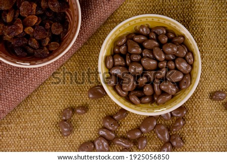 Chocolate Covered Raisin in a bowl top view stock images. Raisins in milk chocolate stock photo. Raisins sultanas still life photo images