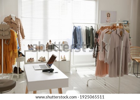 Modern boutique interior with stylish clothes and laptop Royalty-Free Stock Photo #1925065511