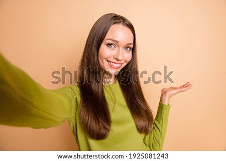 Photo of lovely girl arm hold empty space make selfie wear green sweater isolated beige color background