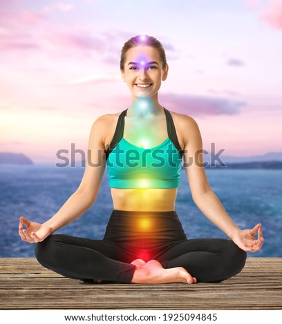 Beautiful young woman practicing yoga near sea  