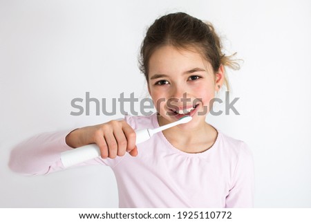 Happy young girl is brushing their teeth with sonic electric toothbrush isolated on white background. Oral hygiene concept with copy space