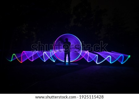 one person standing against beautiful purple circle and green light painting as the backdrop