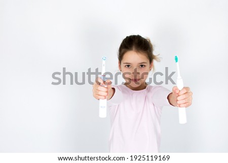 Young girl can´t decide between sonic and rotating oscillating toothbrush isotated on white background. Oral care and white teeth concept with copy space.