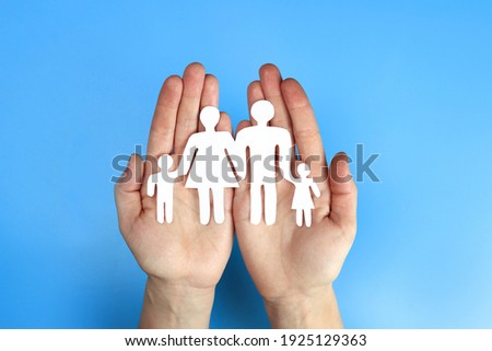 Paper family in hand on a blue background Royalty-Free Stock Photo #1925129363