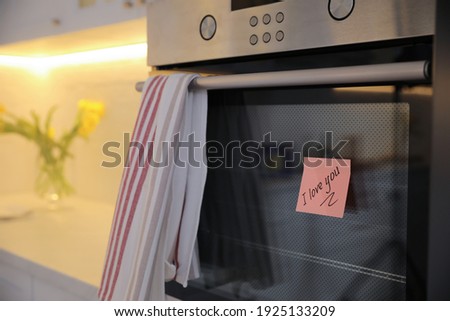 Sticky note with handwritten text I Love You attached to oven door in kitchen. Romantic message