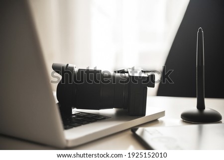 Photographer's workplace with a modern equipment. Mirrorless camera, laptop and graphics tablet. Royalty-Free Stock Photo #1925152010
