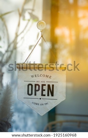 We Are Open Sign and chain hangs on a glass storefront or door due to the shop or retail business , Welcome Come On In.