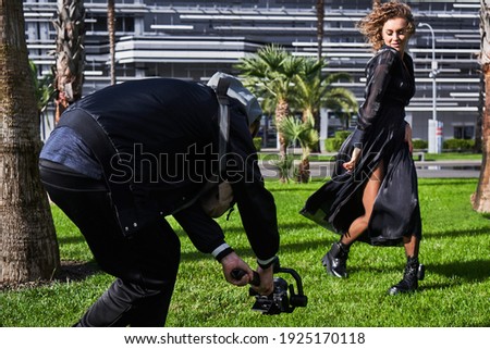 Video camera operator working with fashion model girl outdoors