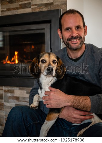 beautiful picture of a man holding his beagle dog in a very tender way inside his home