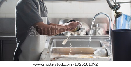 Man washing dish in sink at restaurant.People are washing the dishes too Cleaning solution Royalty-Free Stock Photo #1925181092