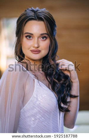 The bride is a European-looking brunette. Single portrait. Wedding makeup and hairstyle. Model. Morning of the bride.