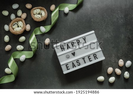 Happy Easter lightbox with colorful Easter eggs in bird's nest on dark background