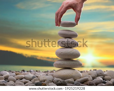 The man's hand is putting gravel on the stone tower. Personal Development Concept Royalty-Free Stock Photo #1925219228