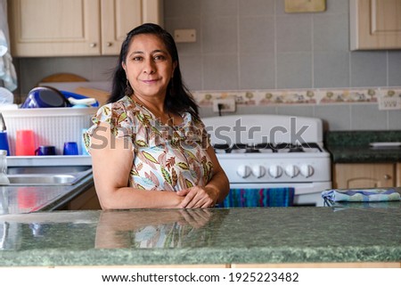 Proud Hispanic woman posing in her kitchen clean-smiling mom standing in the kitchen-woman in the kitchen not cooking Royalty-Free Stock Photo #1925223482