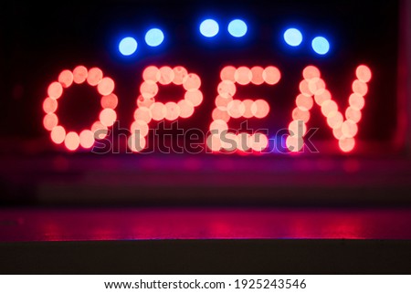 Neon sign with the word 'OPEN' in bold capital letters in a shop window, detail