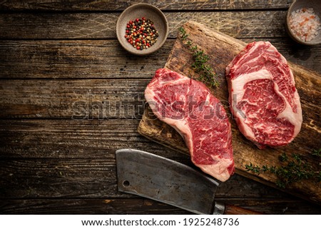 Variety of Fresh Raw Black Angus Prime Meat Steaks New York, Ribeye and seasoning on wooden background, top view Royalty-Free Stock Photo #1925248736