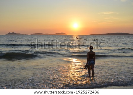 Silhouette of a woman looking the sunset at the beach Royalty-Free Stock Photo #1925272436