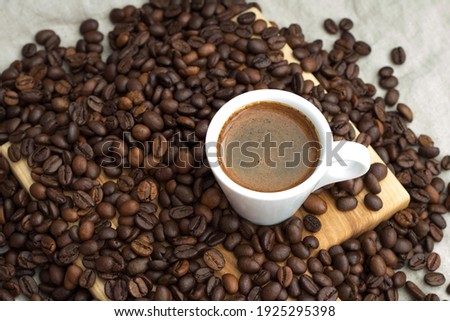 A cup of coffee among selected and calibrated Arabica coffee beans scattered on a napkin, table, blended, top view Royalty-Free Stock Photo #1925295398