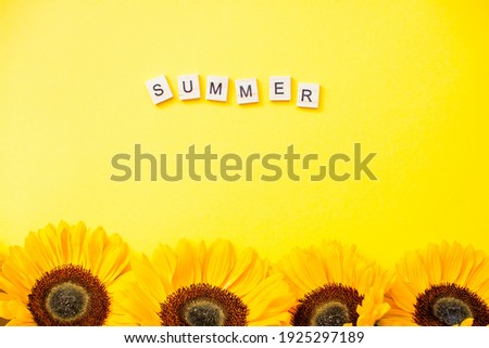 inscription from wooden blocks summer. Bright juicy sunflowers on a bright yellow background. Layout.