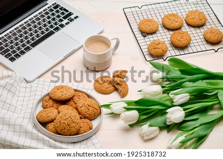 still life with oatmeal cookies tulips coffee and a laptop on a light background