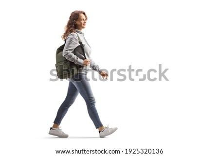 Full length profile shot of a female student in jeans with a backpack walking isolated on white background Royalty-Free Stock Photo #1925320136