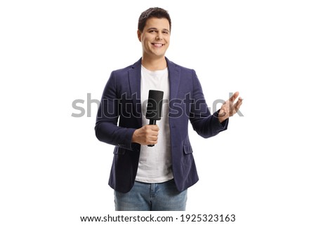 Smiling male reporter holding a microphone and gesturing wiht hand isolated on white background Royalty-Free Stock Photo #1925323163