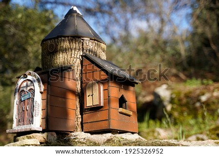 Small wooden and bark building craft in the forest over stone, miniature little home with welcome sign. Side view. 