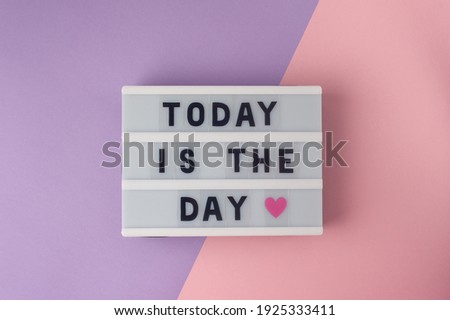 Today is the day - text on display lightbox on purple and pink background.