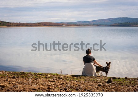 Woman and brown dog near the lake on a beautiful landscape view