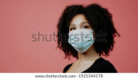 a protective mask against the pandemic, virus, coronavirus, infection on the face. beautiful young woman of afro appearance. looks at posing in a photo studio. Copy space.